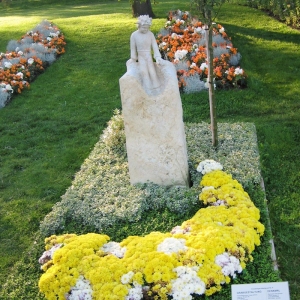 Skulptur des kleinen Prinzen aus weißem Sandstein mit Blumenbepflanzung