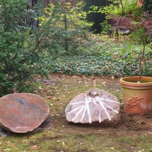 Grabstein in Form einer Elipse aus Findling in Garten
