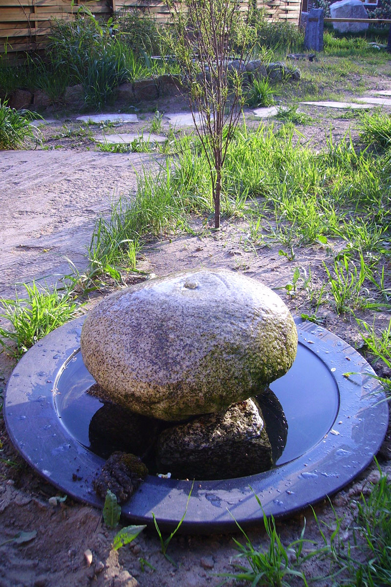 Quellstein aus einem rötlichen Granit Findling in Form eines Pilzes