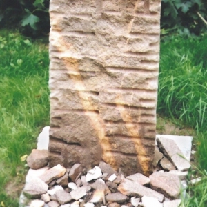 Grabstein als Stele aus rötlichem Porphyrtuff in Form eines Dreiecks