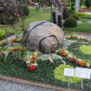 Grabstein in Form einer abgewickelten Zitronenschale in mitten bunter Bepflanzung auf Bundesgartenschau
