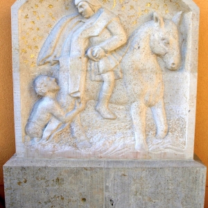 Relief von St. Martin auf dem Pferd mit Bettler vor oranger Wand