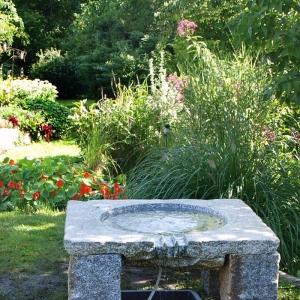 Brunnen aus dunklem Granit in Form eines Tisches in einem Garten